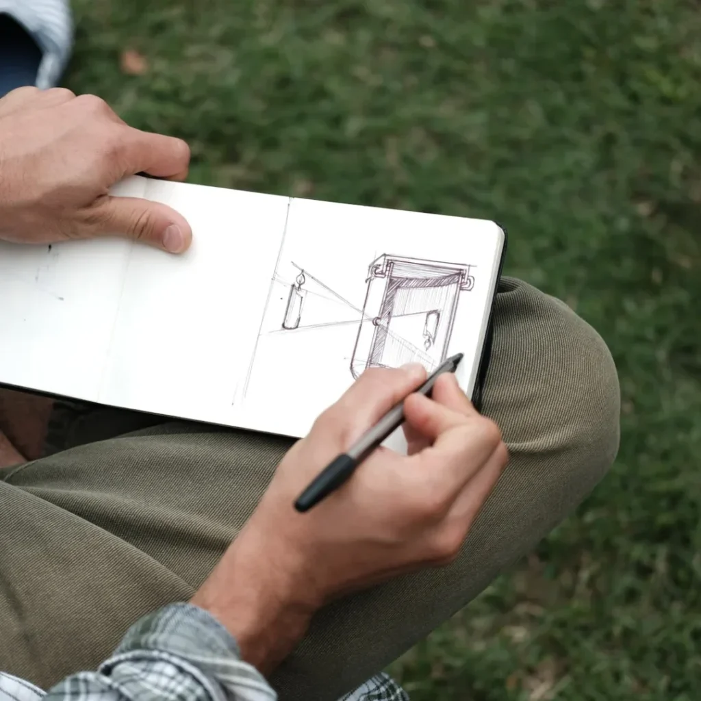 person in brown pants holding black pen writing on white paper