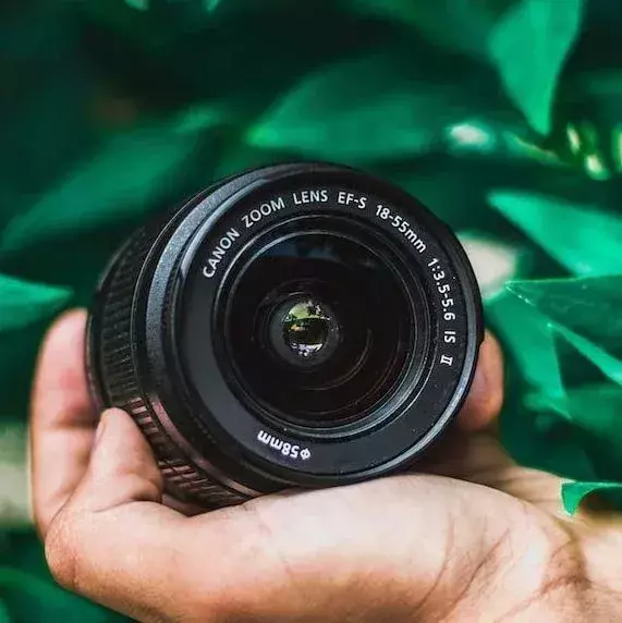 selective focus photography of person holding Canon telephoto lens